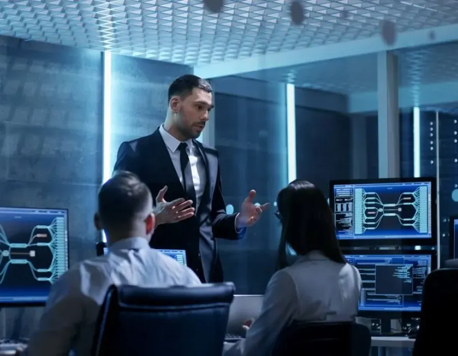 IT manager wearing a suit leading team meeting at desk